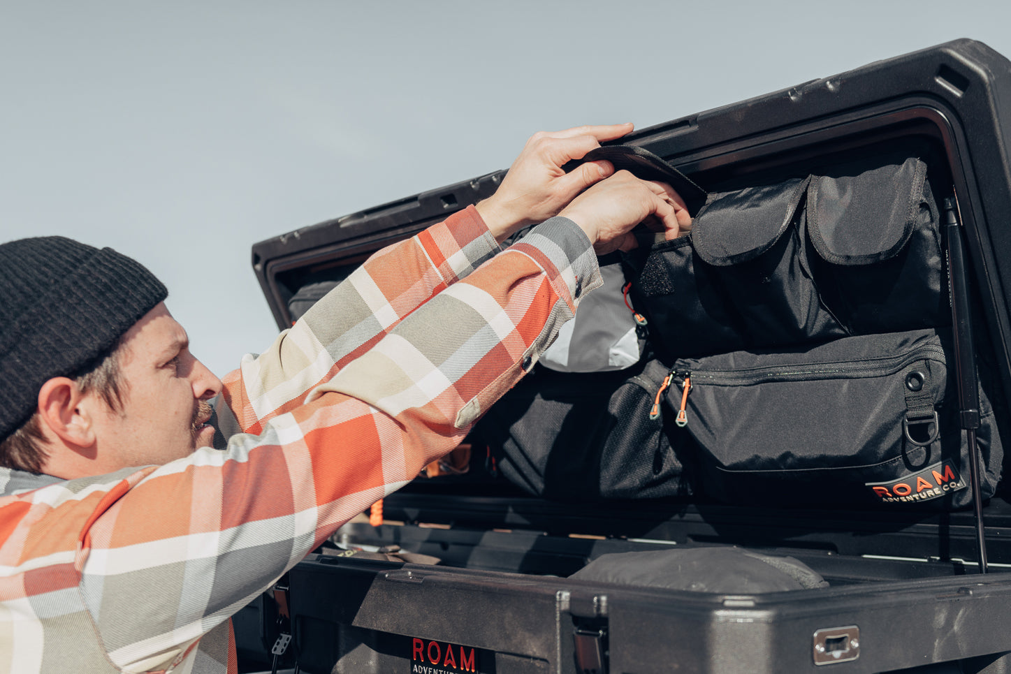 Man arranging gear and tools using the lid organizer in an 83L Rugged Case